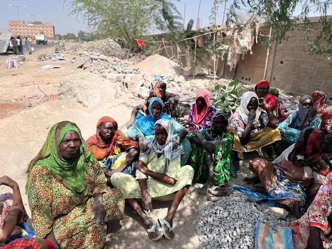 Groupement de femmes bénéficiaires réunies à l'ombre des arbres près des tas de gravier
